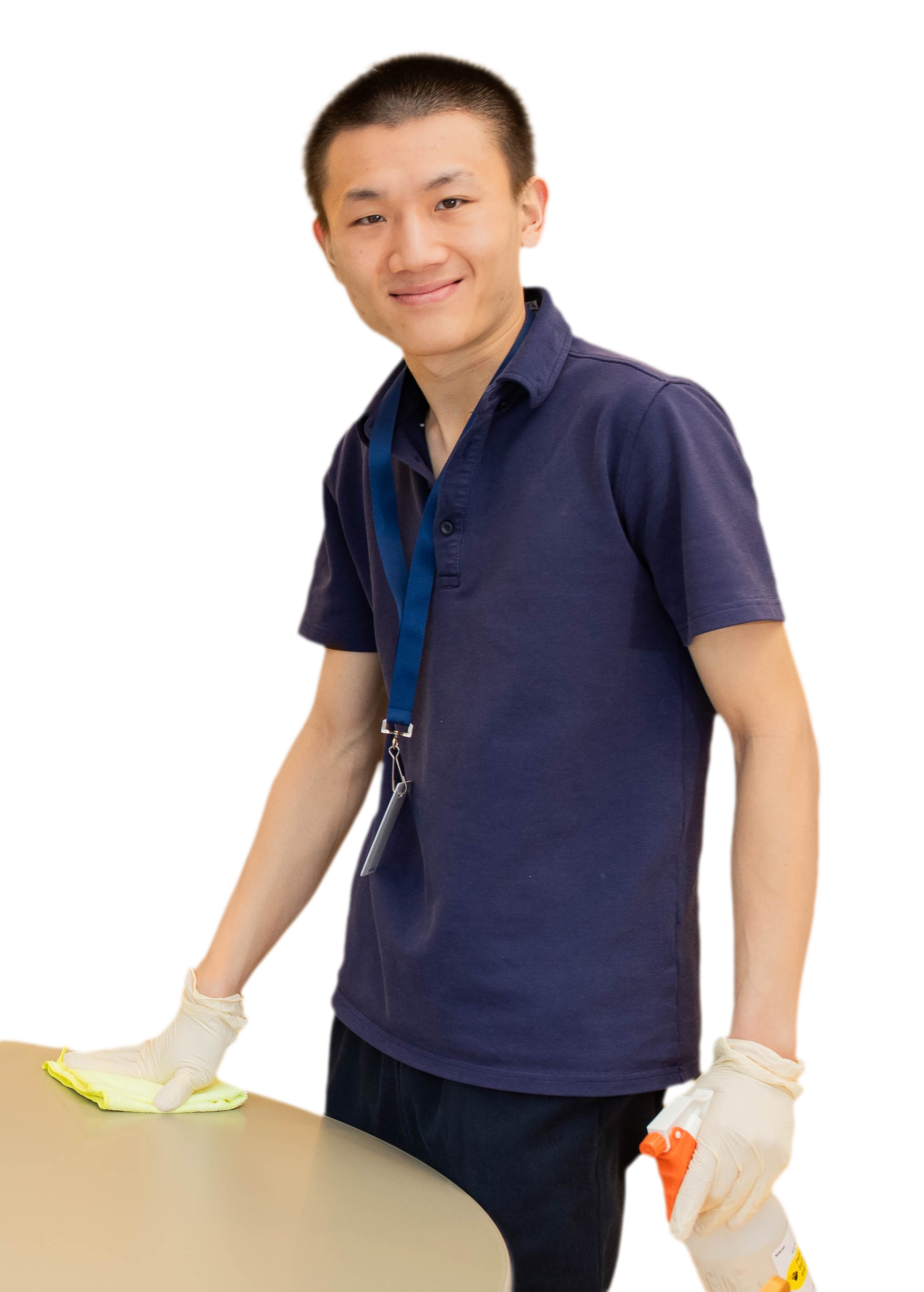 A thin young man wearing a blue shirt and lanyard wiping a table.