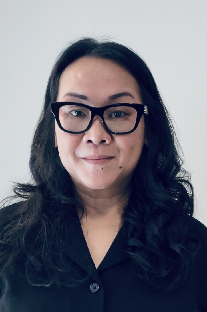A photo of Ofelia Dougal wearing a black button up top and black rimmed glasses.