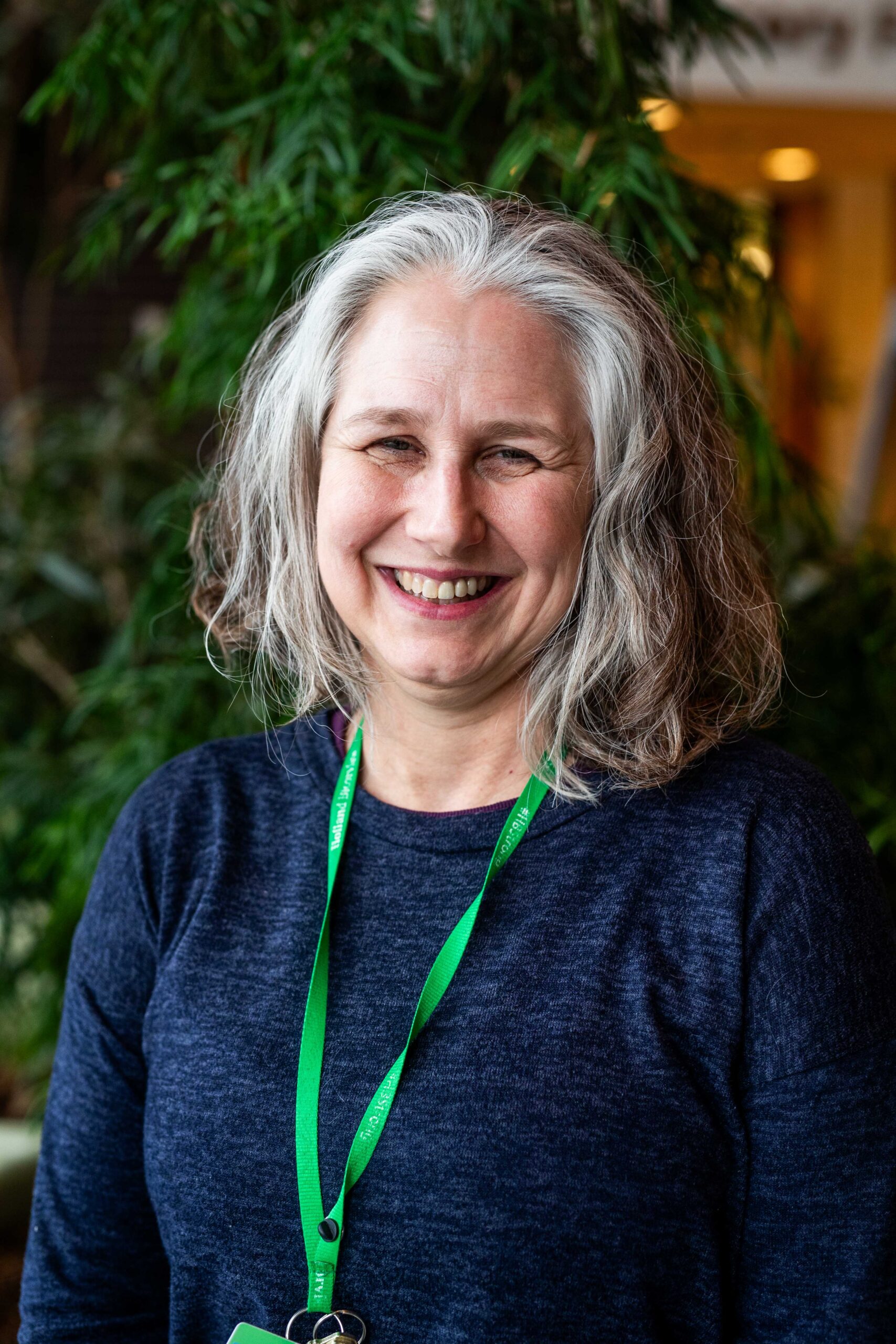 A photo of Carolyn McDougall wearing a blue top and a green lanyard.