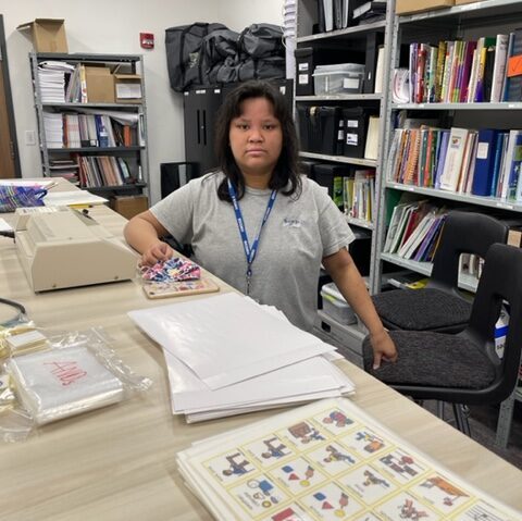A young woman wearing scrubs standing at a tall desk.