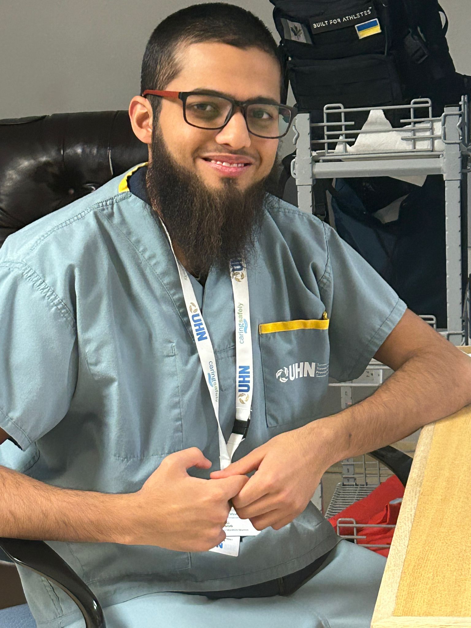 A man with a long beard and glasses wearing UHN scrubs.